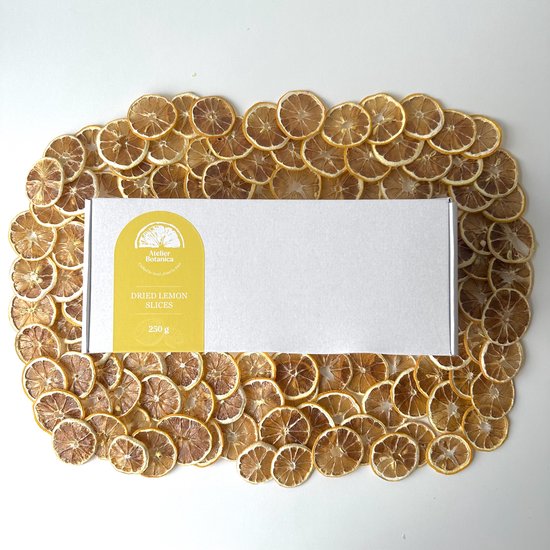 Wit doosje Atelier Botanica met 'DRIED LEMON SLICES 250g' op gele achtergrond, omringd door gedroogde citroenschijfjes.