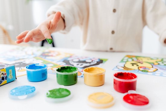Kind handje met groene vingerverf. Potjes rode, gele, groene en blauwe verf, met bijhorende deksels.