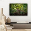 Jaguar in de jungle weergegeven op een canvas aan een muur, naast decoratieve vazen.
