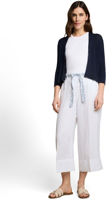 Model met witte culotte en blauw-witte riem, wit T-shirt, marineblauw vestje