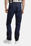 Achterkant van een man met donkerblauwe G-Star Mosa Straight jeans en witte laarzen.