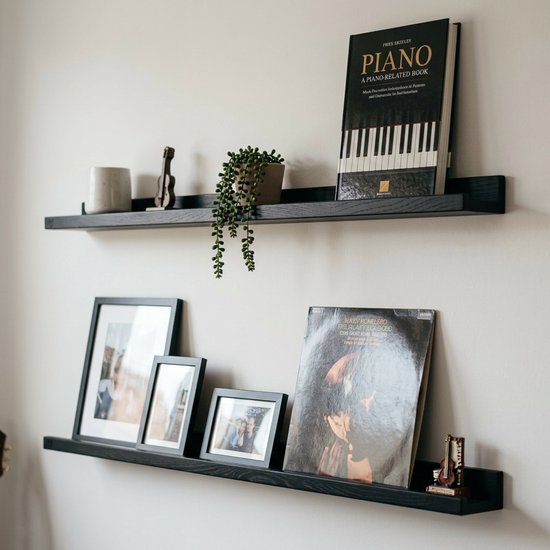 Zwarte zwevende planken met een muziekboek, een vinylplaat, foto's en decoraties.