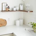 L-vormige donkerbruine houten plank in een keuken met kookgerei en wijnglazen.