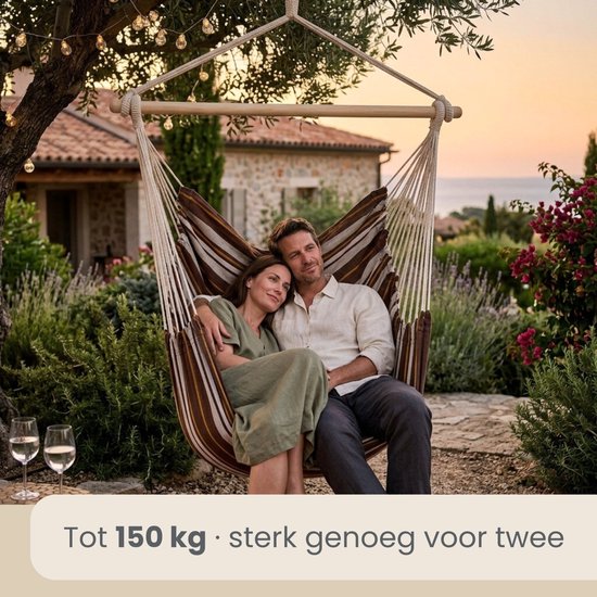 Koppel in gestreepte hangstoel, zittend in een tuin bij zonsondergang.
