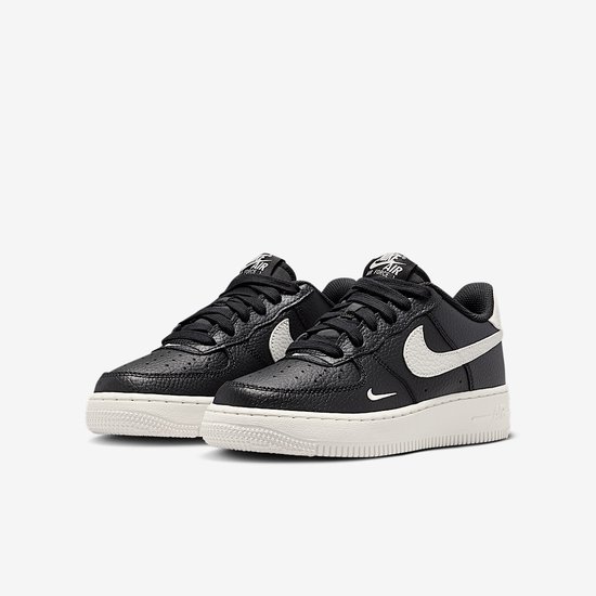 Zwarte Nike Air Force 1 sneakers met witte Nike swoosh en crèmekleurige zool. Leren bovenwerk met reliëf.