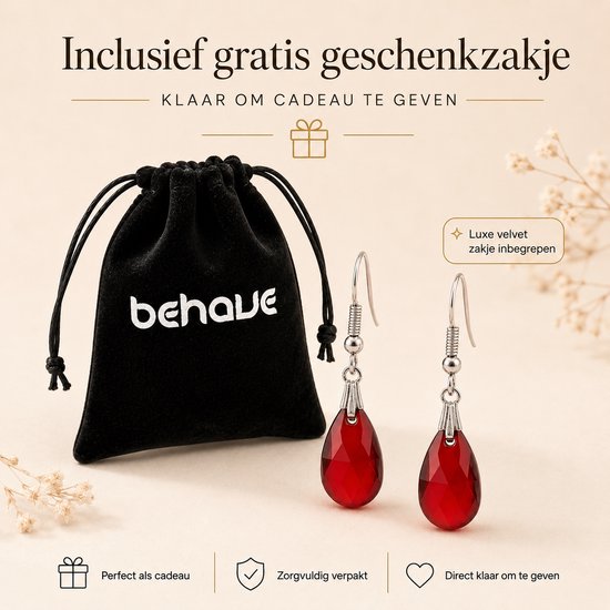 Een zwart fluwelen geschenkzakje met "behave" logo, naast twee zilverkleurige oorbellen met rode druppelvormige hangers.