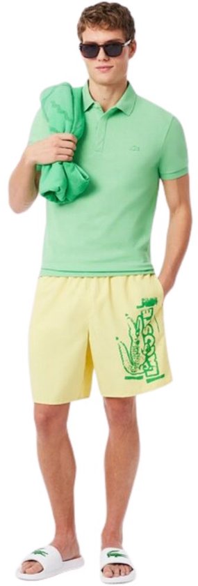 Man met gele shorts met groen krokodillenlogo en witte slippers.