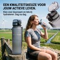 Matgrijze King Mungo drinkfles met tekst en een vrouw die ervan drinkt in een landelijke setting met windmolens.