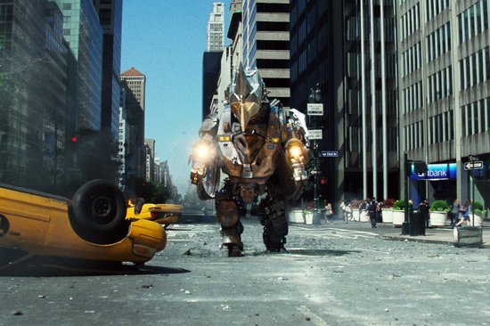 Een grote robot met een harnas loopt door een stadstraat met een omgekiepte gele taxi.
