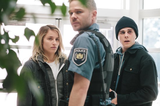 Dianna Agron, een politieagent en Jared Abrahamson kijken ernstig.