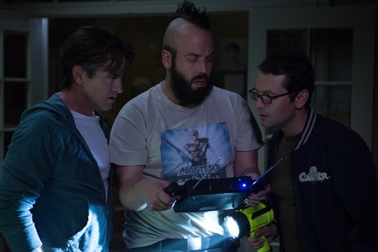 Drie mannen kijken naar een apparaat met een lampje en een scherm.