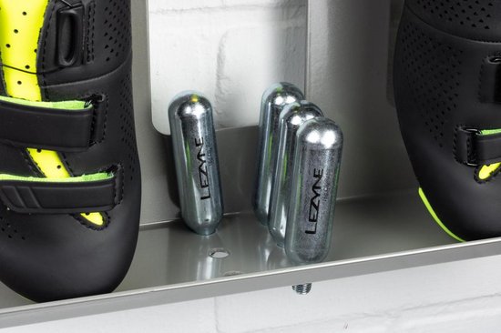 Close-up van CO2-patronen en zwarte racefietsschoenen met limegroene accenten op een zilverkleurig Stasdock-rek.