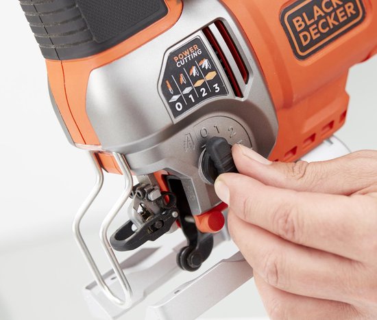 Vinger draait aan de instelknop van een oranje en zilveren Black+Decker decoupeerzaag.