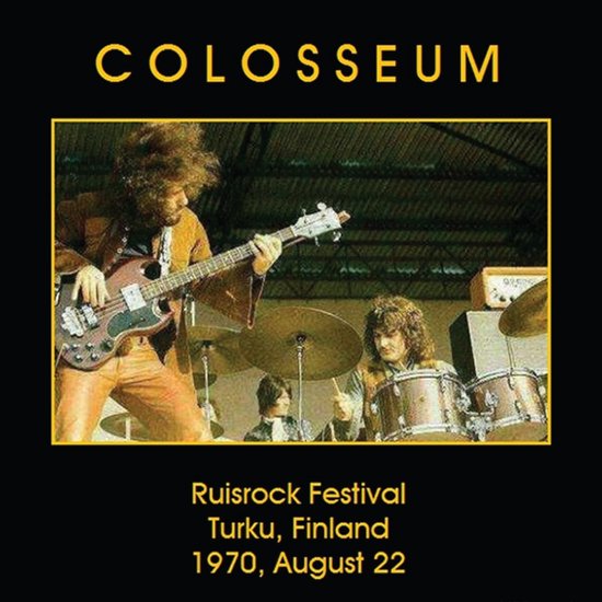 Colosseum bandleden spelen op het Ruisrock Festival in Turku, Finland op 22 augustus 1970. De zanger speelt basgitaar en draagt een bruin overhemd en oranje broek.