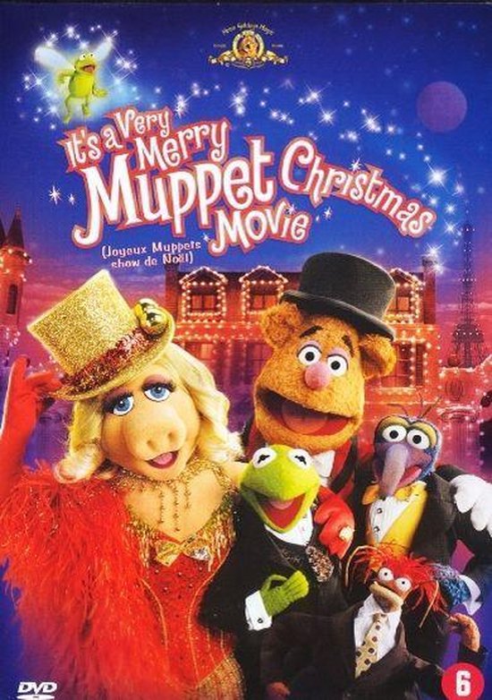 De Muppets Miss Piggy, Kermit, Fozzie, Gonzo en Rizzo in feestelijke kerstkleding, met een gebouw op de achtergrond.