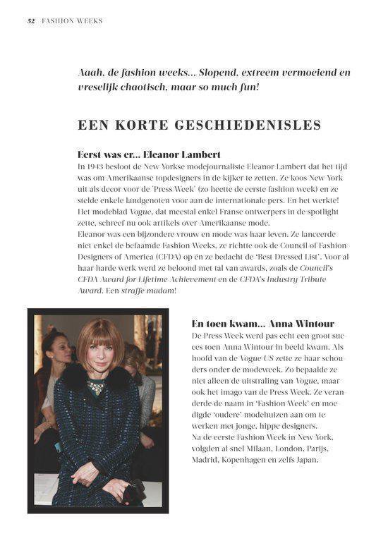 Anna Wintour in grijs met zwart jasje, staand met een glimlach.