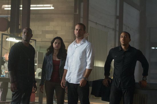 Vier personen staan in een industriële ruimte. Van links naar rechts: Tyrese Gibson, Michelle Rodriguez, Paul Walker, Ludacris.