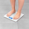 Pieds sur une balance personnelle numérique blanche avec écran bleu affichant '20.9 kg'.