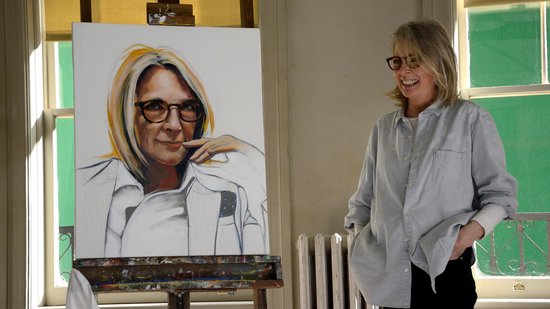 Diane Keaton lacht naast een schilderij van zichzelf.