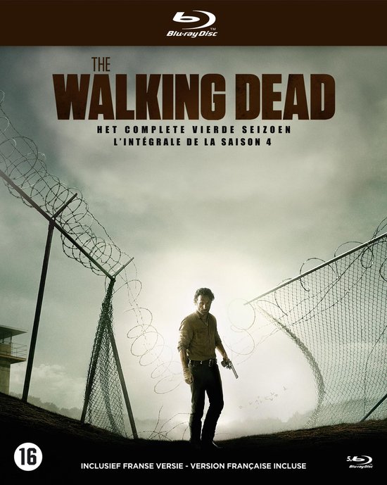 Rick Grimes met pistool, voor een hek met prikkeldraad. "THE WALKING DEAD HET COMPLETE VIERDE SEIZOEN L'INTÉGRALE DE LA SAISON 4"