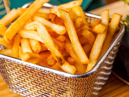 Een vierkant RVS frietmandje vol met goudbruine frietjes.