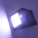 Zwarte solar wandlamp, verlicht de muur met een fel wit licht en blauwe LED's aan de zijkant.