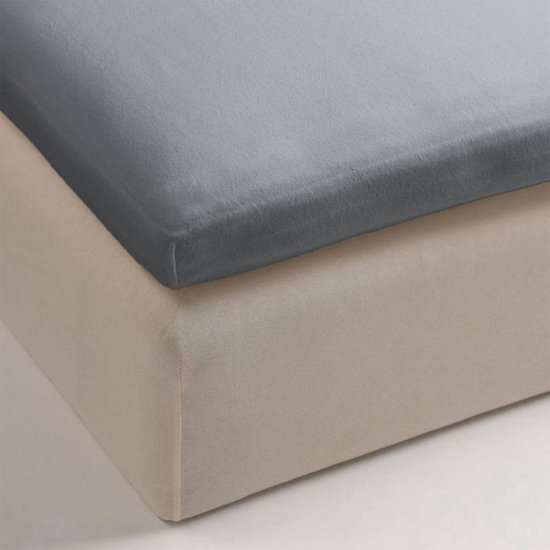 Een grijs jersey topper hoeslaken op een beige hoes van een boxspring.