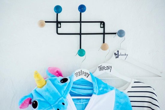 Kledingrek met kinderkleding: blauw unicorn onesie, witte jas en gestreepte shirt. Hangers zijn gelabeld met dagen.