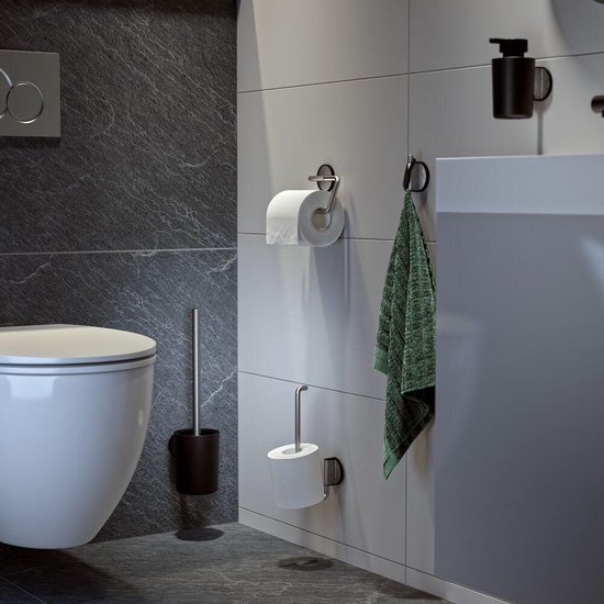 Une brosse de toilette avec un support foncé à côté d'une cuvette de toilette blanche, avec deux porte-rouleaux de papier toilette muraux.