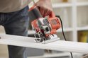 Oranje en zilveren Black+Decker decoupeerzaag met variabele snelheid, gebruikt op sierlijst.
