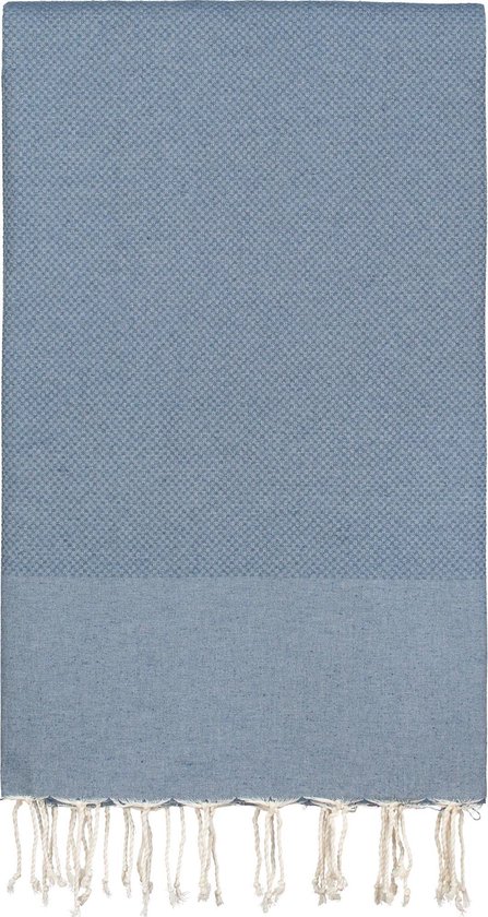 Een rechthoekige, denimblauwe plaid met aan de bovenkant een ruitpatroon, een effen deel eronder en franjes aan de onderkant.