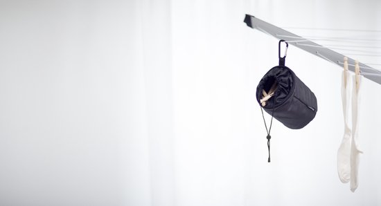 Zwart Brabantia wasknijperzakje hangt aan een waslijn, met sokken ernaast.