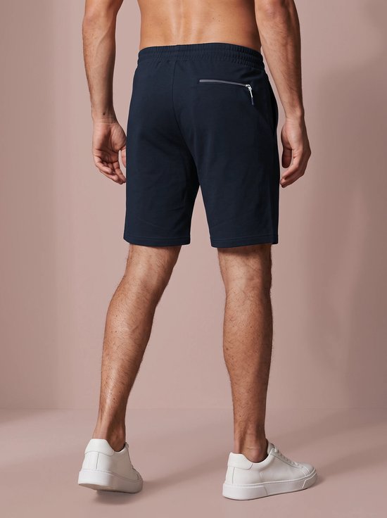 Achteraanzicht van marineblauwe sportshort met een ritszak aan de rechterkant en elastische tailleband.
