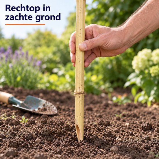 Hand die een bamboe tuinfakkel in zachte tuingrond plaatst met een schepje op de achtergrond.