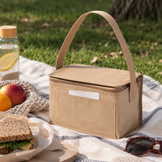 Beige rechthoekige koeltas van gerecycled papier met draaghengsel op een picknickkleed.