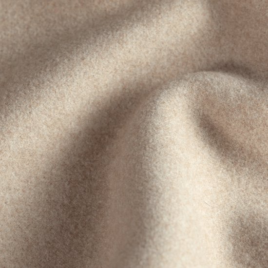 Close-up van zandkleurige, zachte wollen stof met natuurlijke plooien.