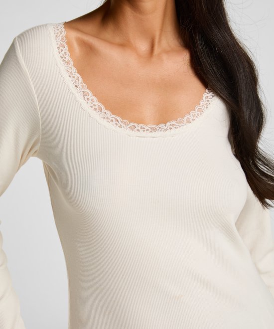 Detailopname van het crème-witte ribgebreide shirt met een elegante kanten halslijn en lange mouwen.