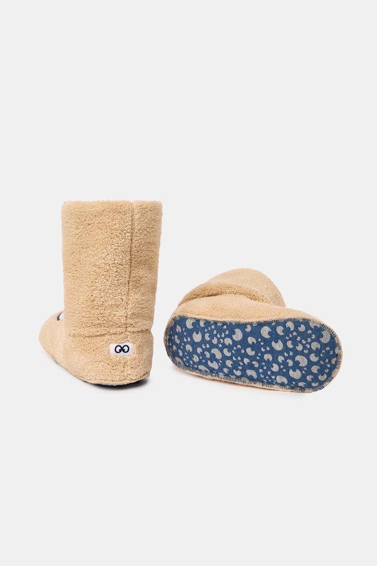 Pantoufles beiges hautes en peluche avec une semelle bleue à motif lune. L'arrière d'une pantoufle montre un logo.