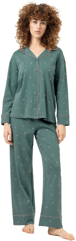 Model in groene pyjama met lange mouwen en all-over kleine roze bessenprint. De pyjama heeft een knoopsluiting en roze biezen.