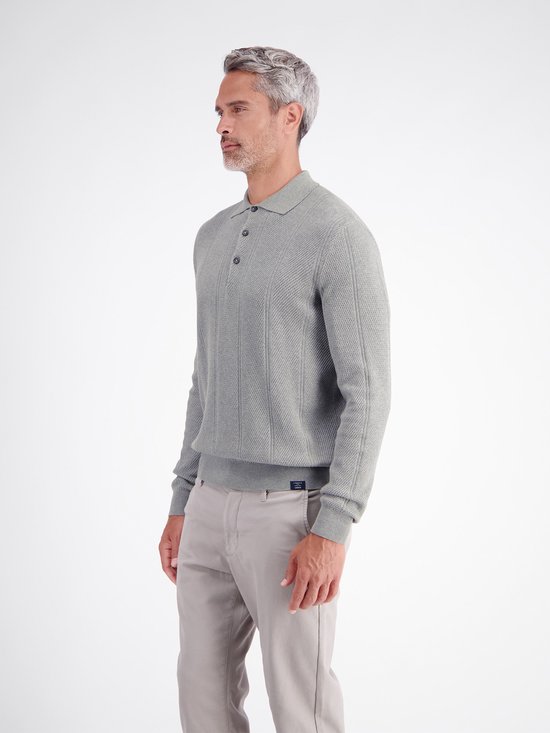 Zijaanzicht van de grijze polo met textuur en verticale strepen, gecombineerd met een beige broek.