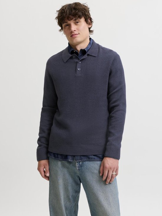 Man met lange mouwen, donkerblauwe gebreide polo, denim overhemd en spijkerbroek.