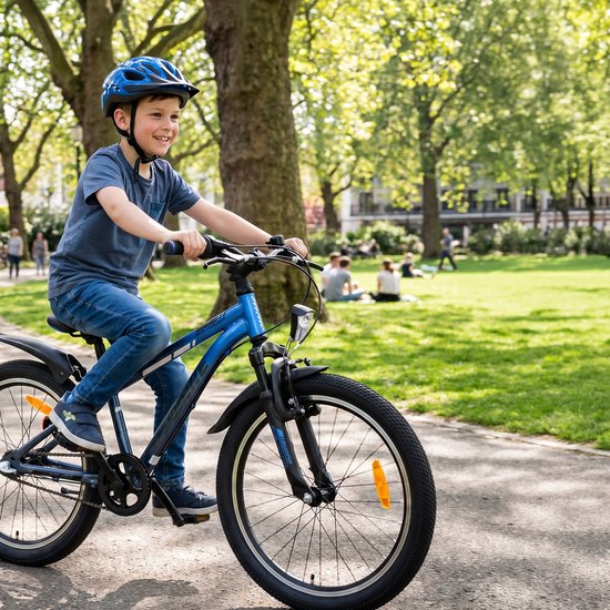 Jongen in grijs t-shirt en blauwe helm op een blauwe kinderfiets in een zonnig park.