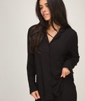 Detailopname van model in zwarte jersey pyjamajas met knopen en borstzak.