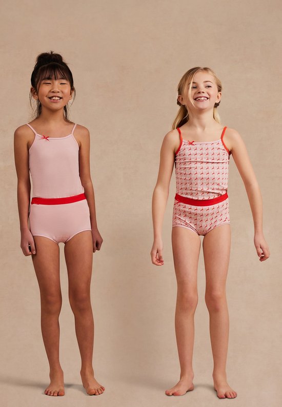 Twee meisjes in ten Cate hemdjes en shorts: een in effen roze, de ander met roze-oranje hertjesprint.