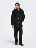 Zwarte parka met capuchon en crèmekleurige voering, gedragen door een model.