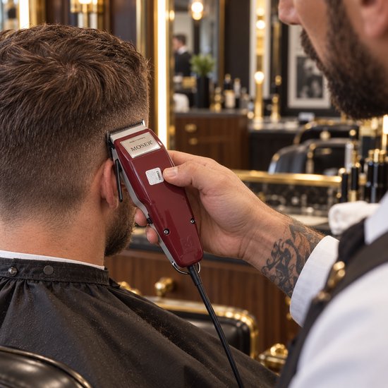 Kapper trimt haar met een bordeauxrode Moser 1400 tondeuse, gezien vanaf de achterkant.