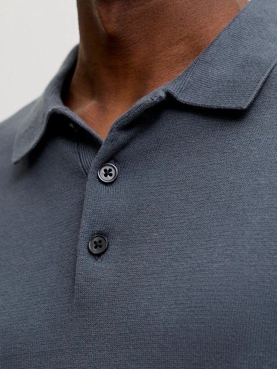 Detail van de donkerblauwe gebreide poloshirt met knopen.