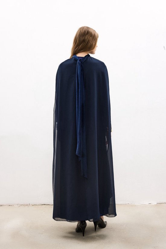 Achterkant van een lange, donkerblauwe jurk met hoge hals, wijde chiffon mouwen en strikdetails in de nek.