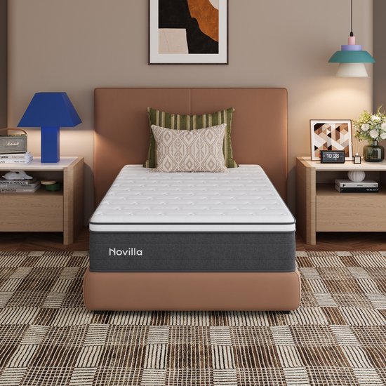 Eenpersoons Novilla-matras op een bruin bedframe in een modern ingerichte slaapkamer.
