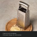 Roestvrijstalen rasp met ergonomische handgreep en fijne rasp, naast een hoop geraspte kaas.